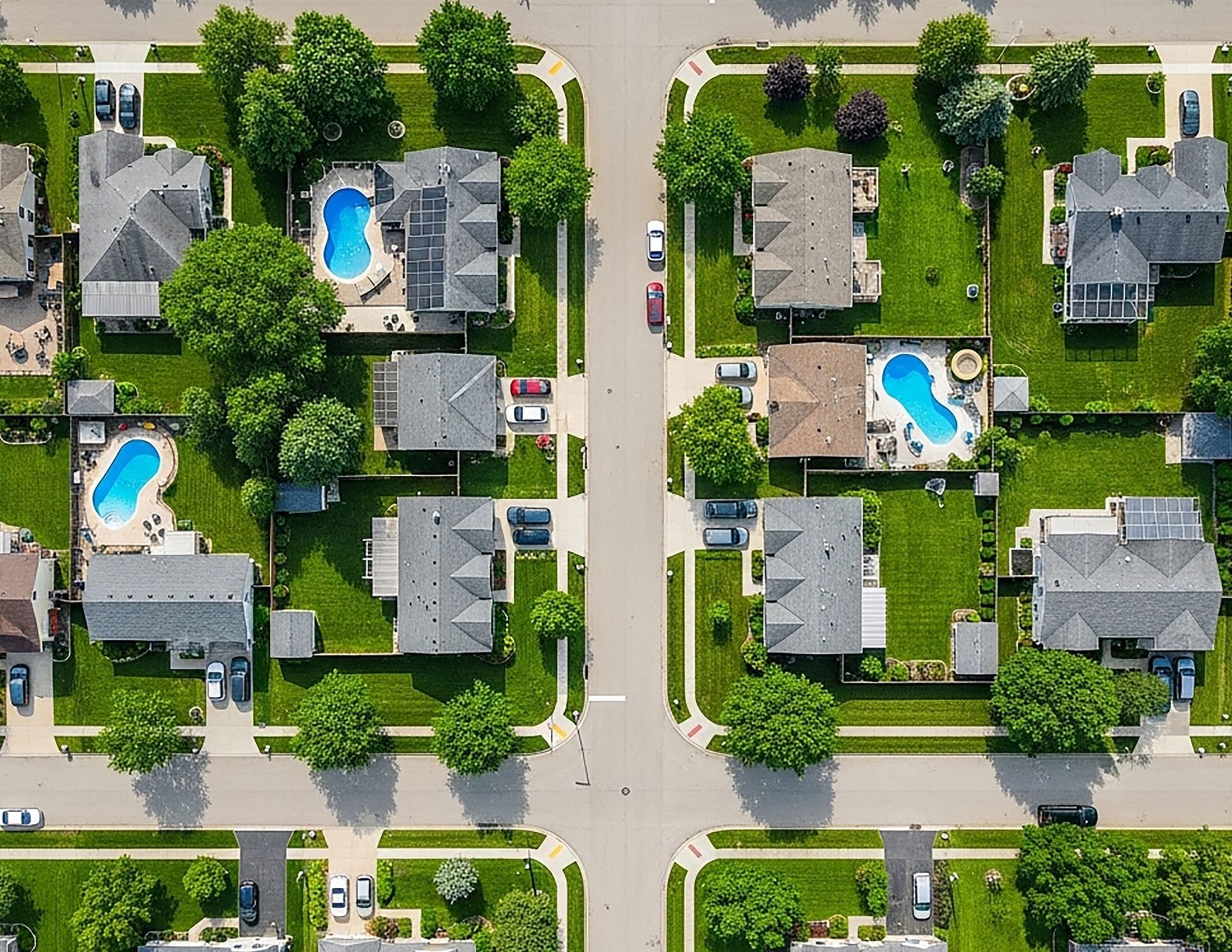 Straight-down aerial view of a tree-lined Long Island neighborhood with backyard pools